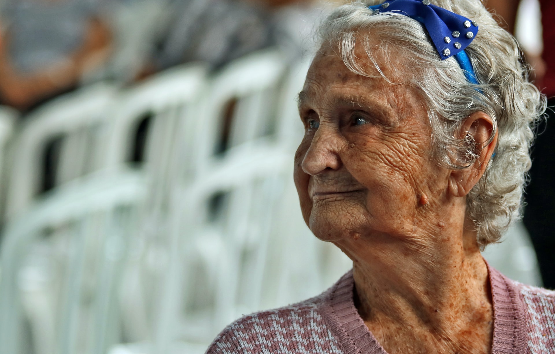 Smiling elderly woman with white hair and headband.