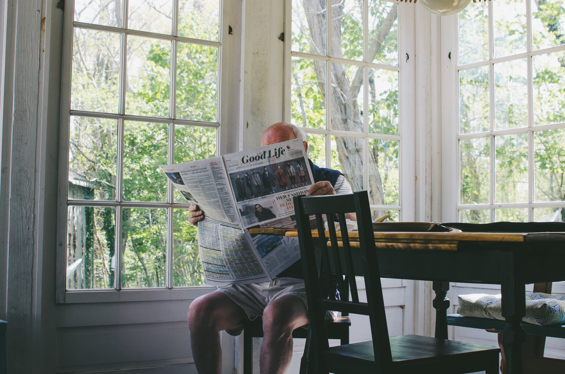 Elderly man reading a newspaper indoors