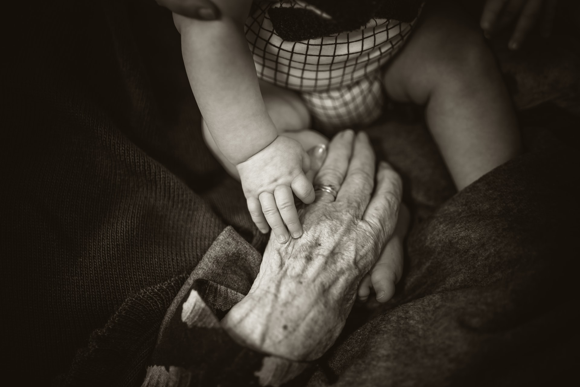 A baby's hand touching an elderly person's hand