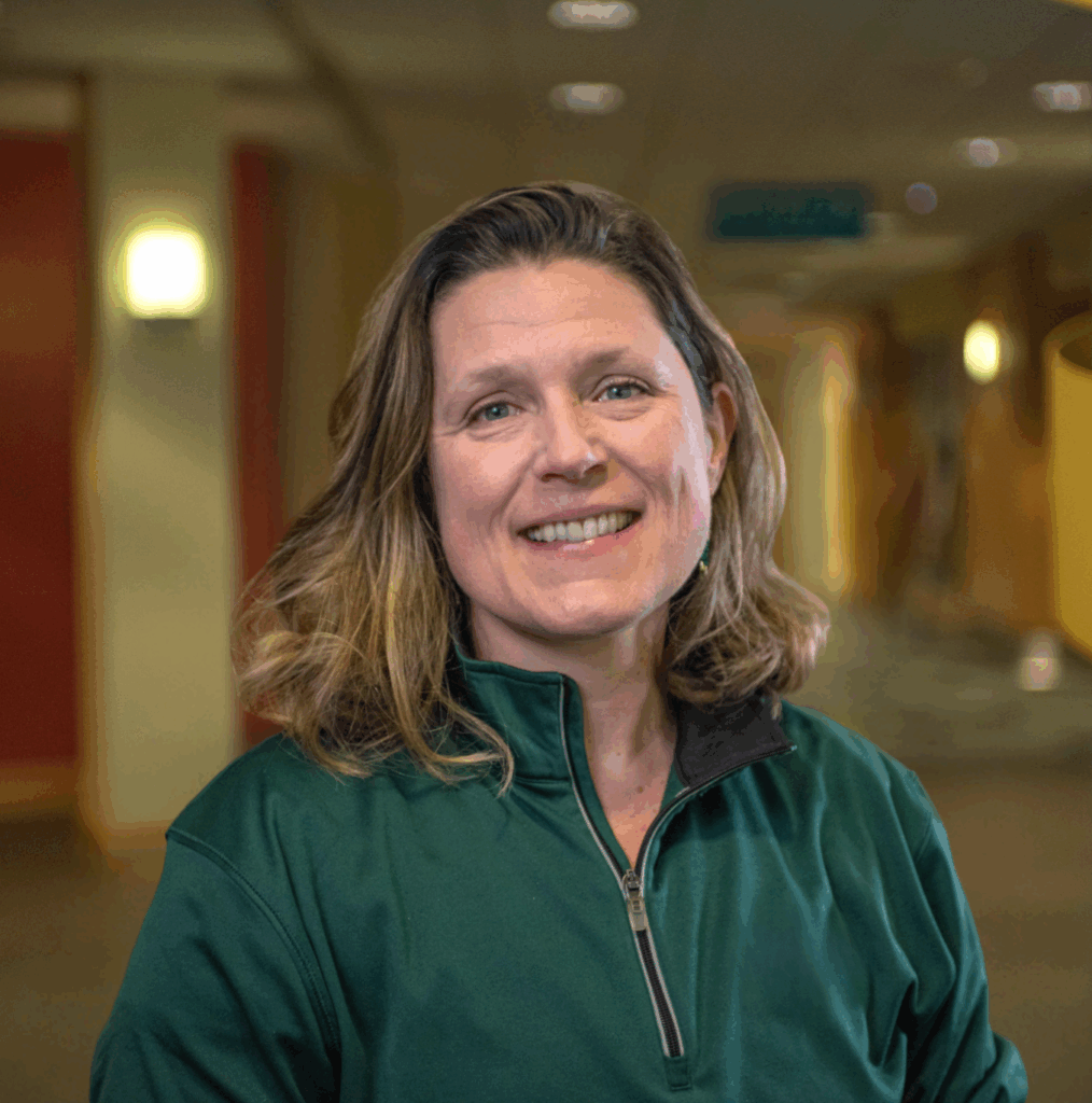 Staff member smiling in a facility interior.