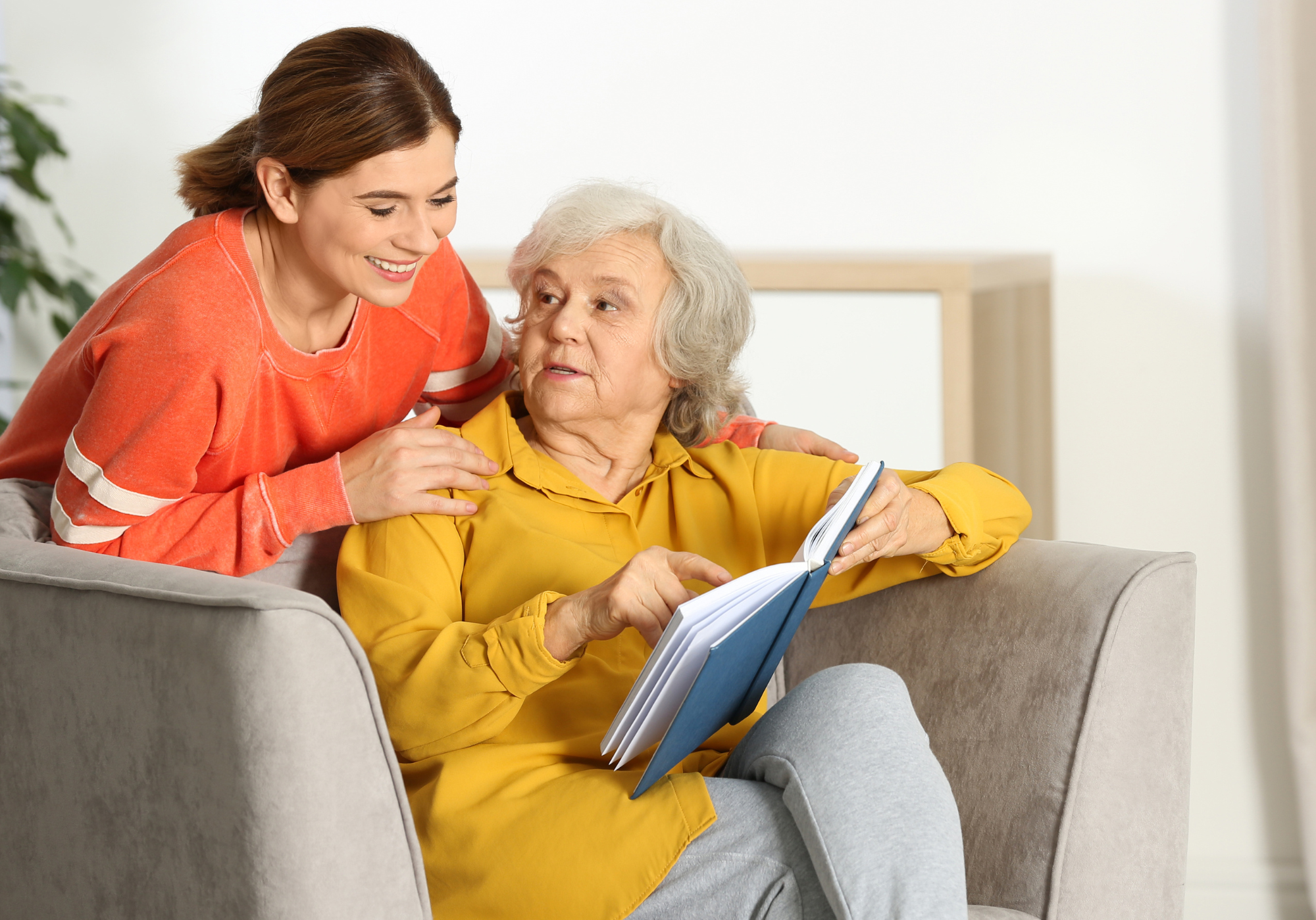 Caregiver and resident interacting and reading together.