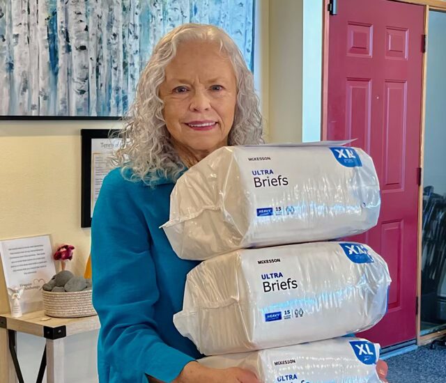 Senior resident holding packages of supplies.