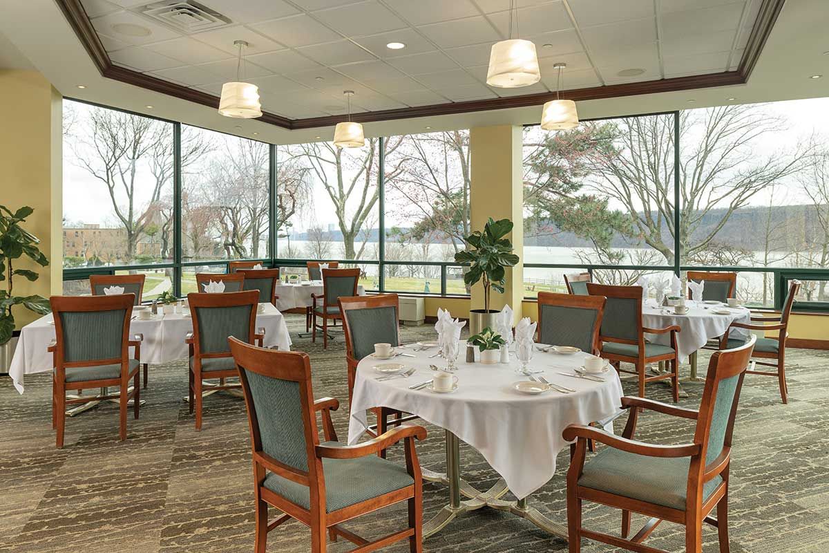 Bright dining room with tables and chairs by large windows.