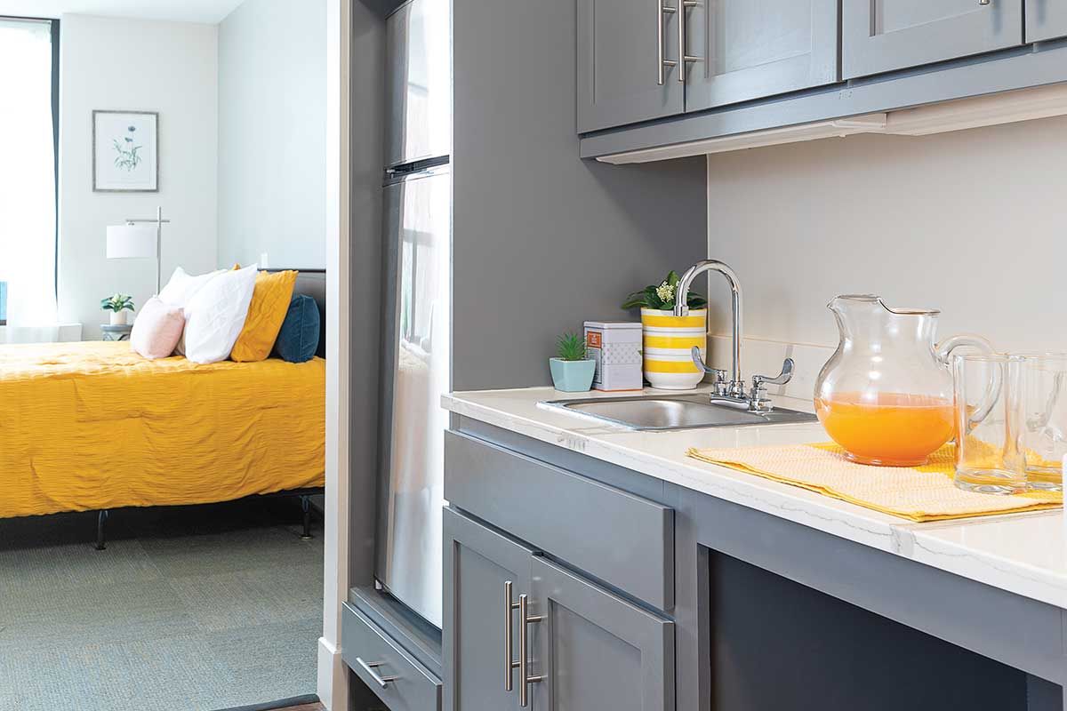 Bright kitchen area with orange drink and bed