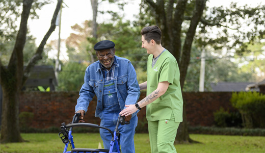 Senior man with walker and caregiver outdoors