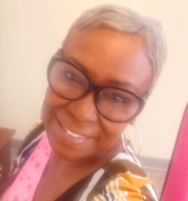 A smiling resident with short hair and glasses.
