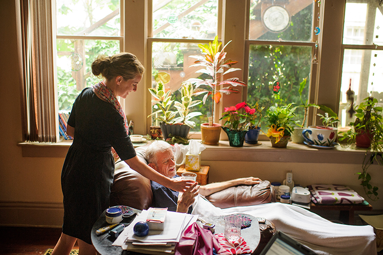 Staff member assisting an elderly resident indoors.