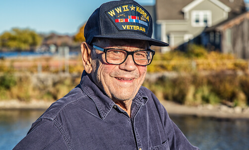 Elderly veteran smiling outdoors by a lake