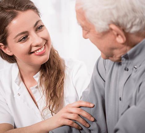 Caregiver smiling while attending to an elderly man