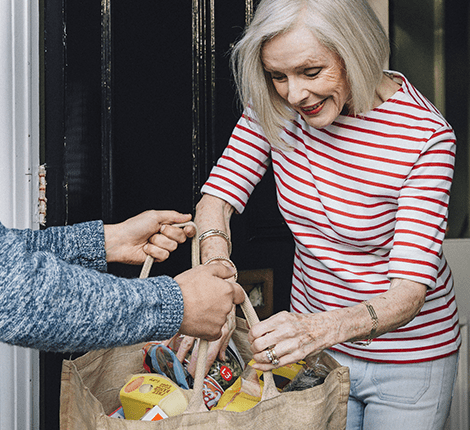 Senior woman smiling while receiving a bag of goods