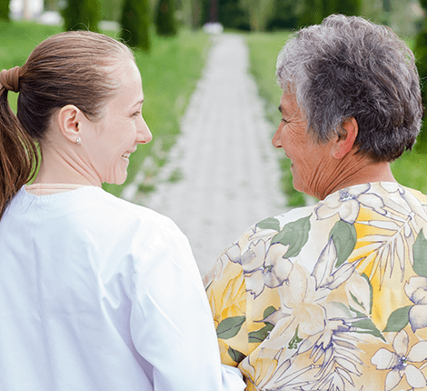 Caregiver and resident walking in a garden path
