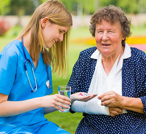 A caregiver assisting an elderly woman outdoors