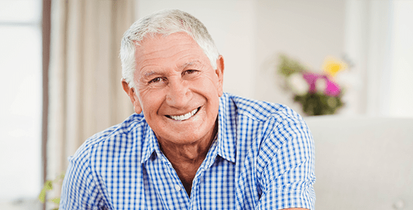 Smiling elderly man with plaid shirt indoors.