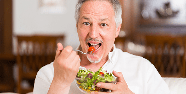 Elderly man enjoying a healthy salad indoors.