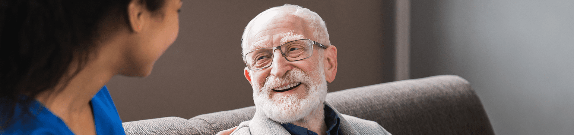 Smiling elderly man with caregiver indoors