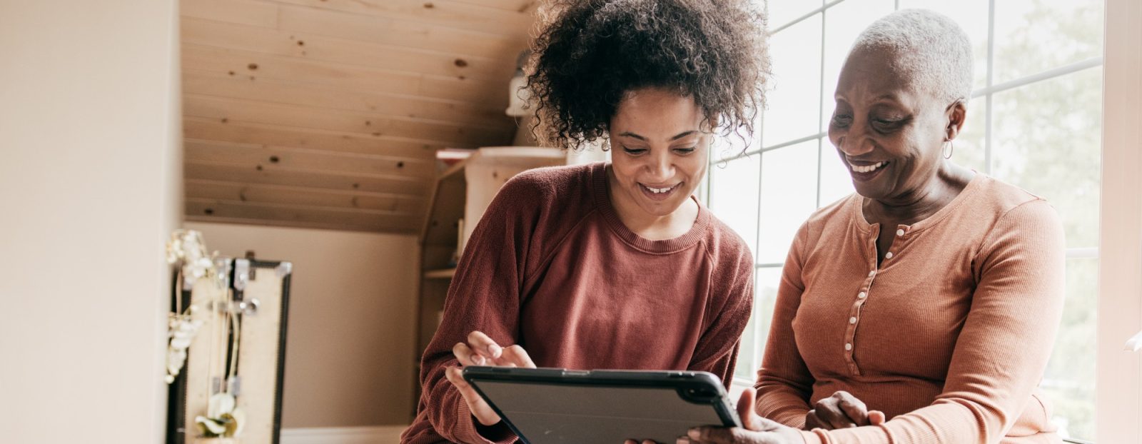 Two women sharing a moment with a tablet indoors.