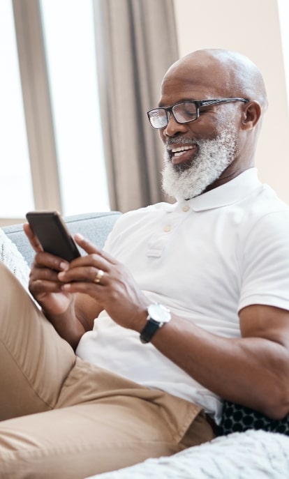 Senior man enjoying his phone on a couch
