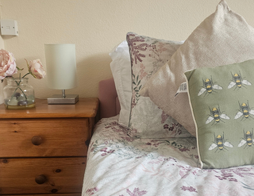 Cozy bedroom with floral bedding and decorative pillows.