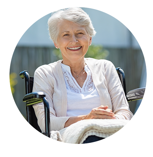 Senior woman smiling in a wheelchair outdoors.