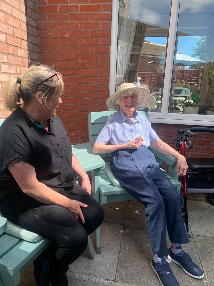 Resident and staff member enjoying outdoor seating.