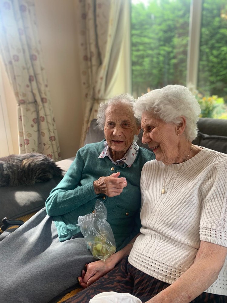 Two elderly women enjoying each other's company indoors.