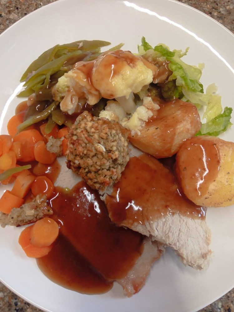 A plated meal with turkey, vegetables, and cornbread