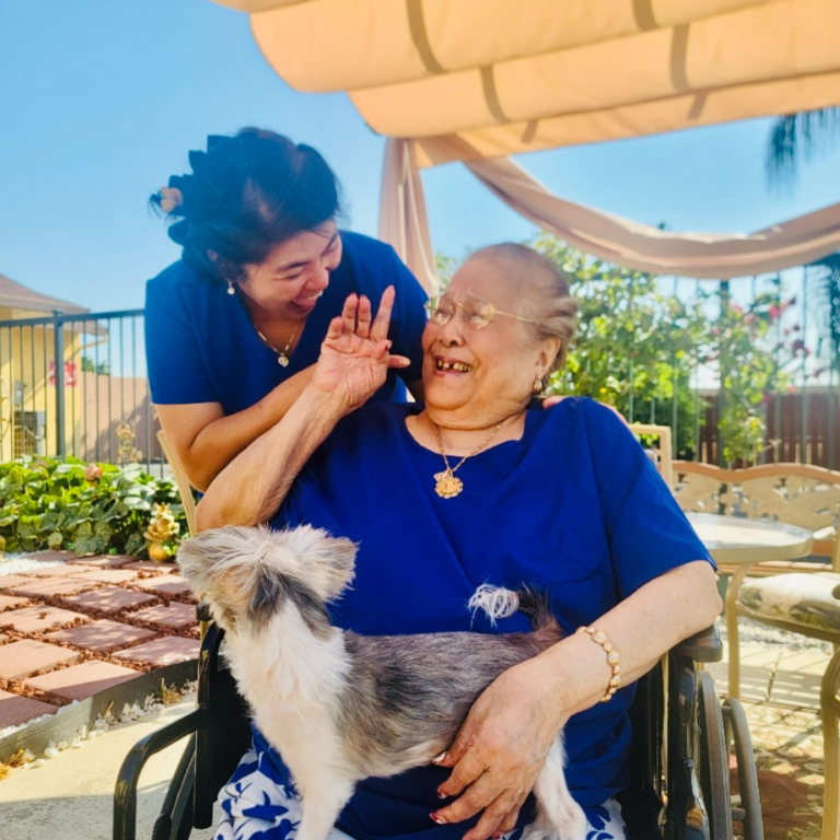 Staff interacting joyfully with a resident and a dog.