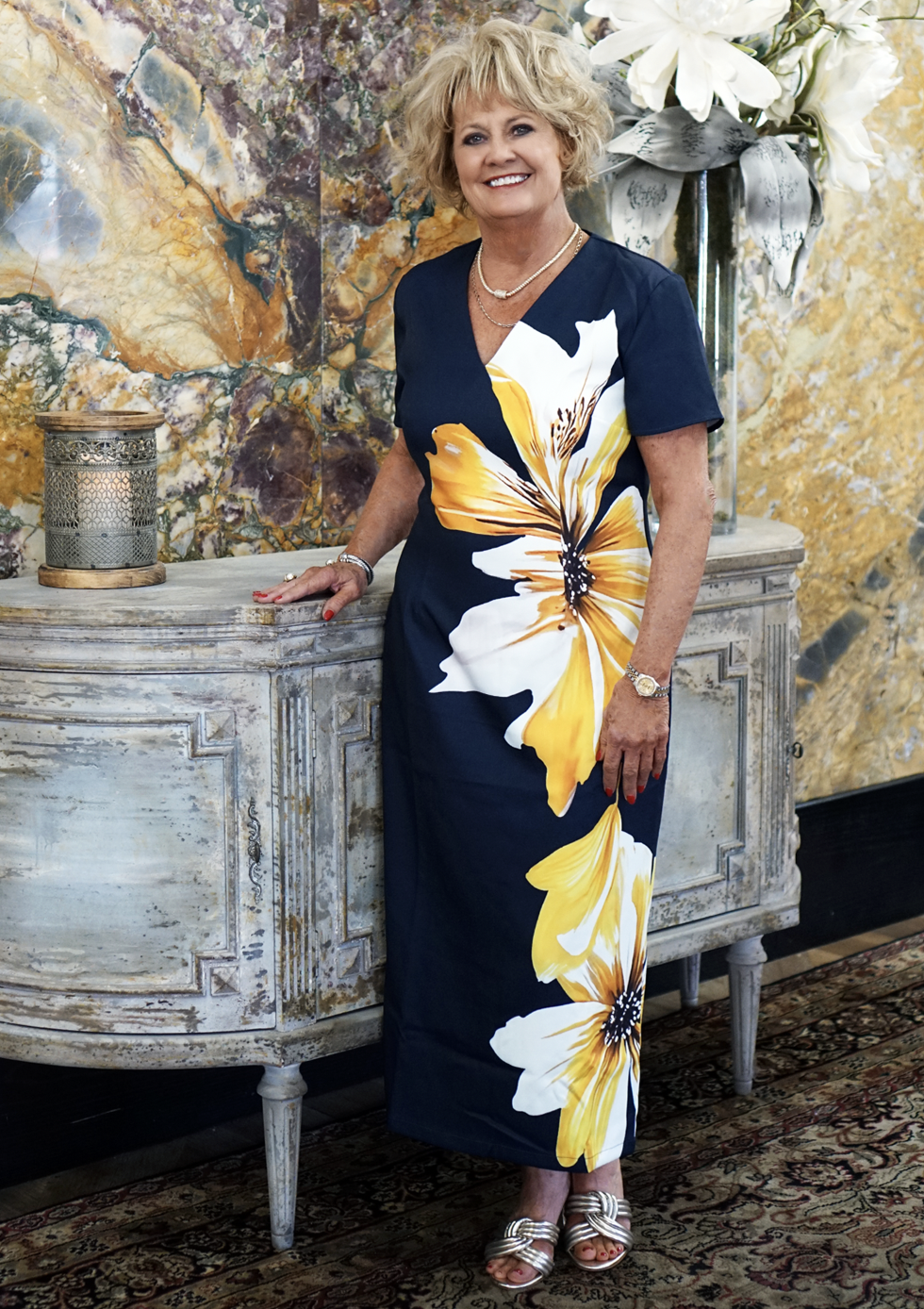 Woman in floral dress near decorative furniture.