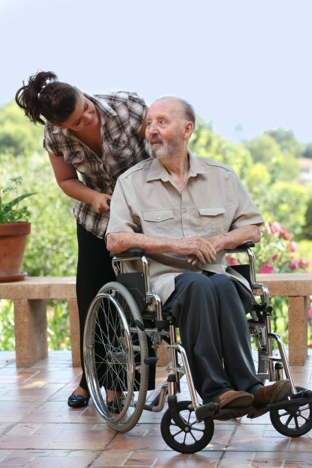 Caregiver assisting a resident in a wheelchair outdoors