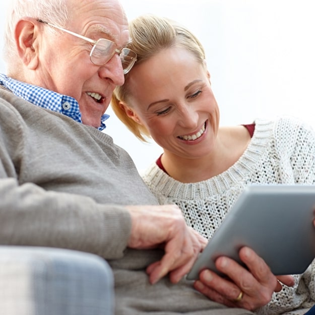 A senior man and caregiver using a tablet together