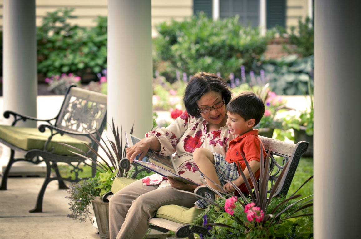 A female resident reading with a young boy in a garden