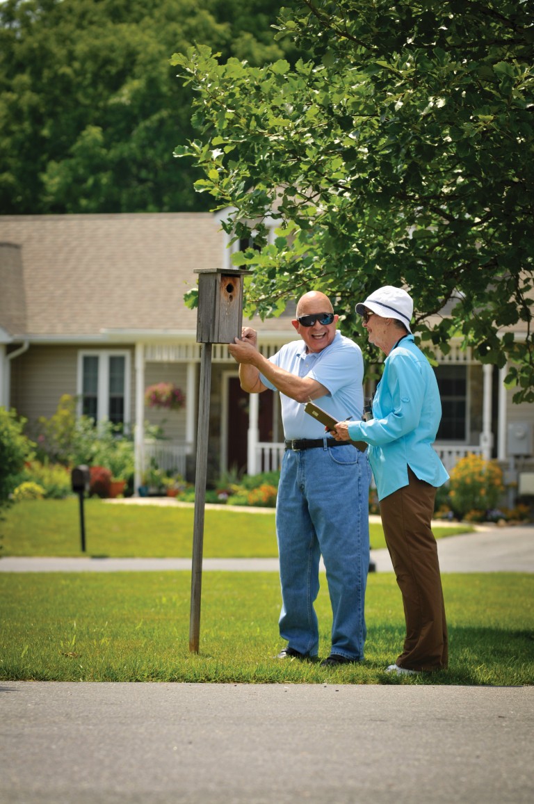 Two residents enjoying outdoor activity by a birdhouse