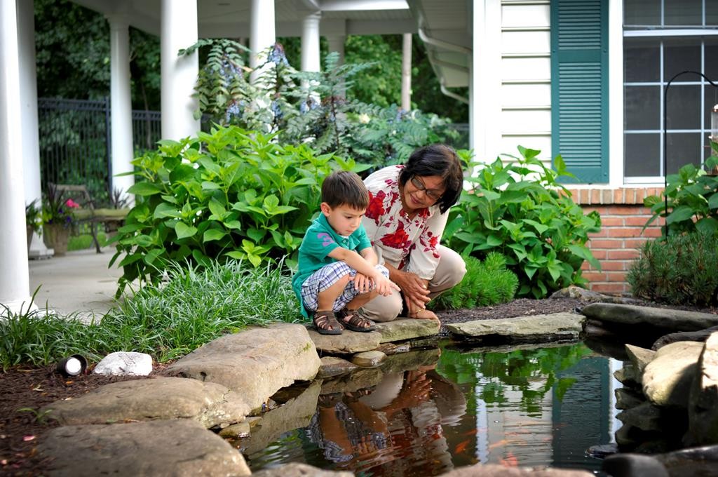 A woman and child by a pond in the facility gardens