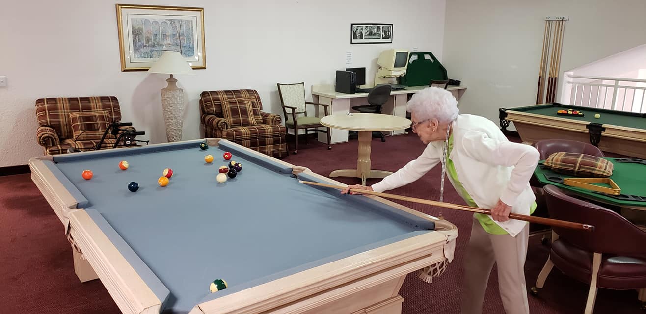 A resident playing pool in an activity room