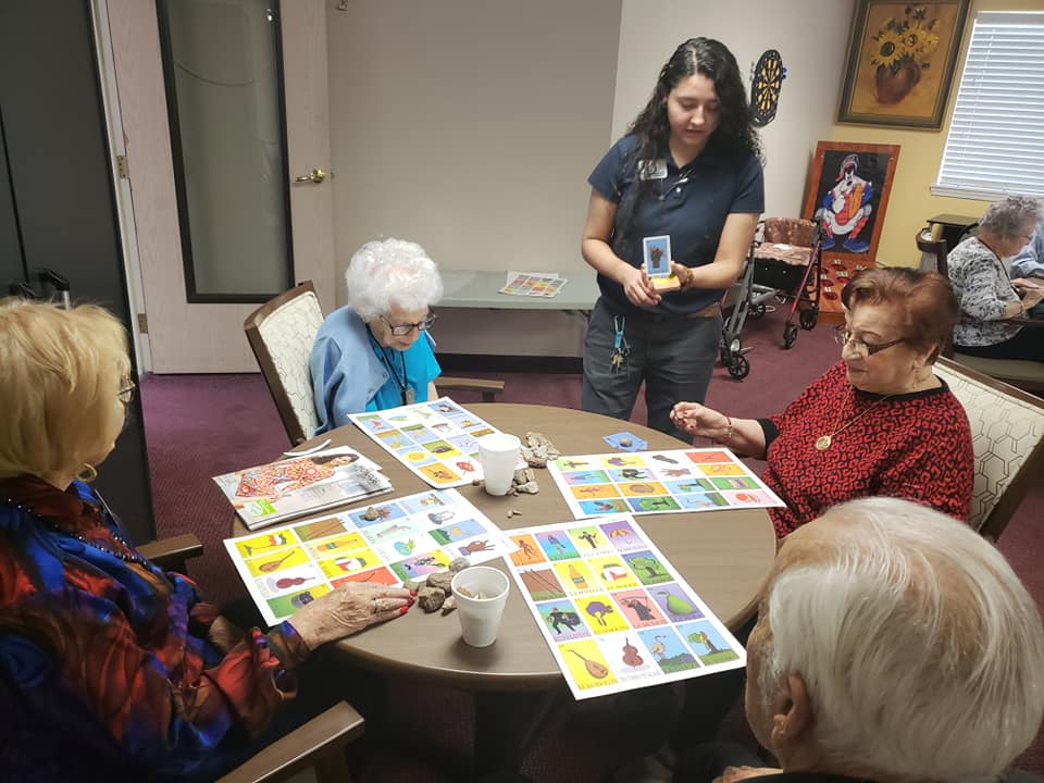Residents participating in a bingo game with staff guidance