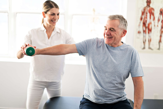 A therapist assisting a senior man with exercises