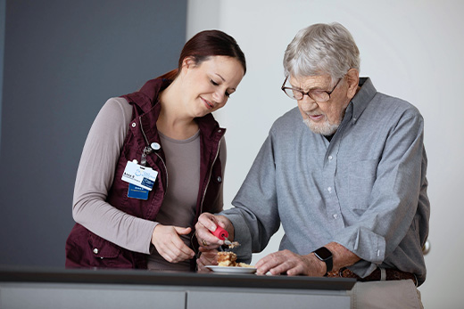 Staff assisting a senior resident with food preparation