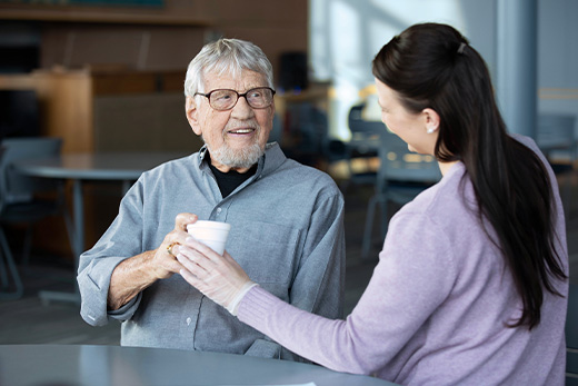A caregiver handing a cup to a resident in a communal area