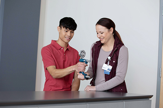 Staff assisting a resident with therapy equipment in an interior setting
