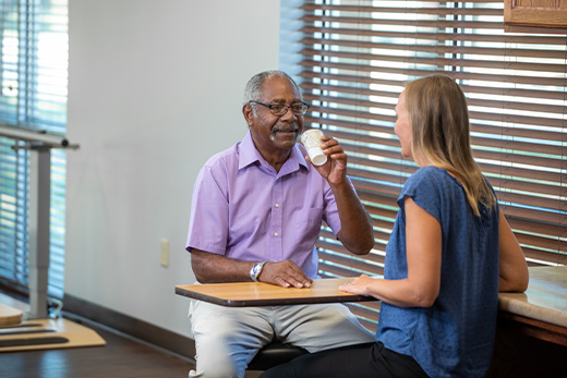 A resident enjoying a drink with a staff member in a common area