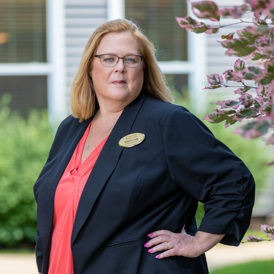 Staff member posing outdoors with greenery