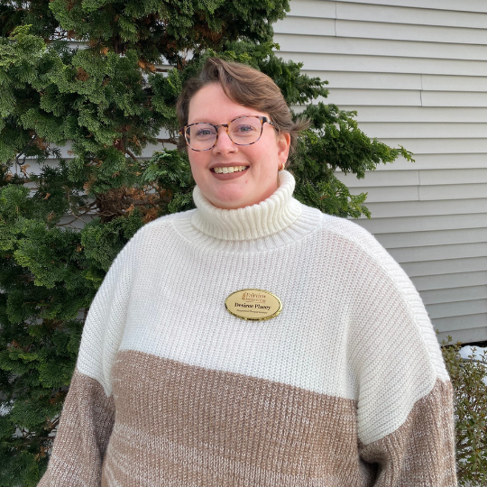 Staff member standing outside near evergreen trees