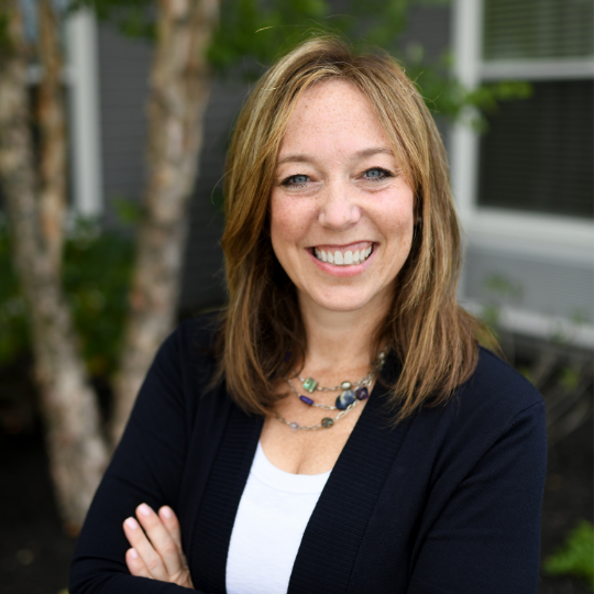 Smiling staff member with crossed arms outdoors