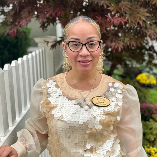 Staff member posing outdoors near a garden