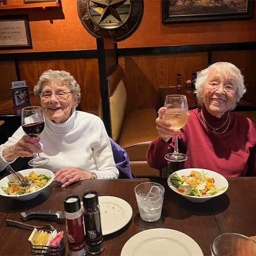 Two residents enjoying a meal with drinks at a table