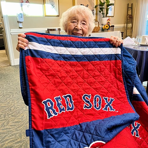 Resident joyfully displaying a blanket in a common area