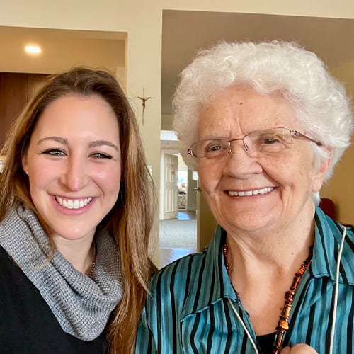A smiling resident and staff member in a bright interior