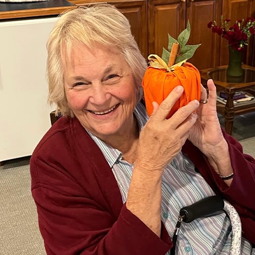 Resident holding a decorative pumpkin craft.