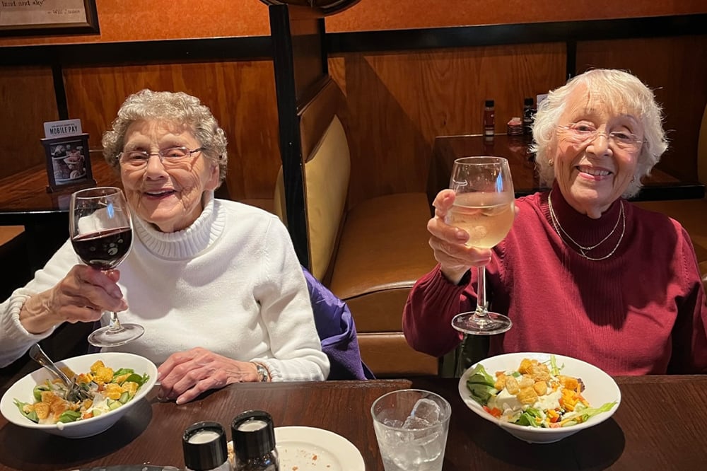 Two residents toasting with glasses at a dining table