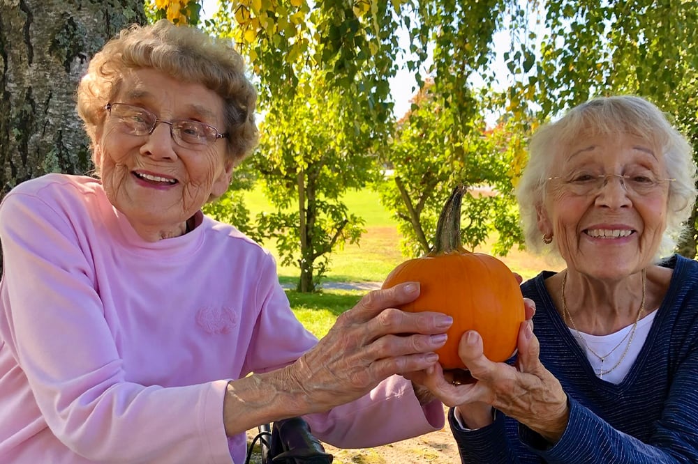 Two residents enjoying a pumpkin in the garden